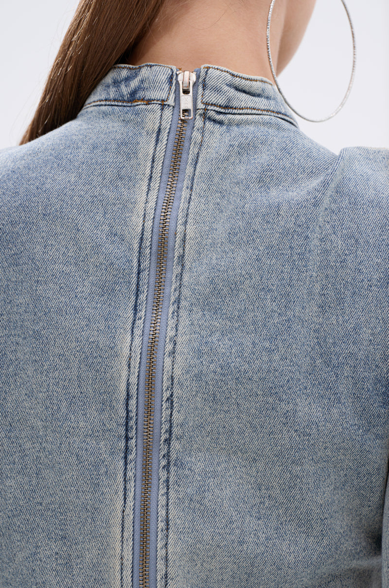 Close-up of the back of a person in the WAIT FOR U DENIM BOW BLOUSE TOP, featuring a light blue hue and exposed back zipper. Visible are part of their long brown hair and a large silver hoop earring.