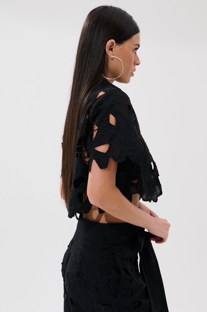 A woman with long straight brown hair and large hoop earrings wears the DOLLY FLORAL BUTTON DOWN BLOUSE with matching high-waisted pants, standing in profile against a plain light background. 3
