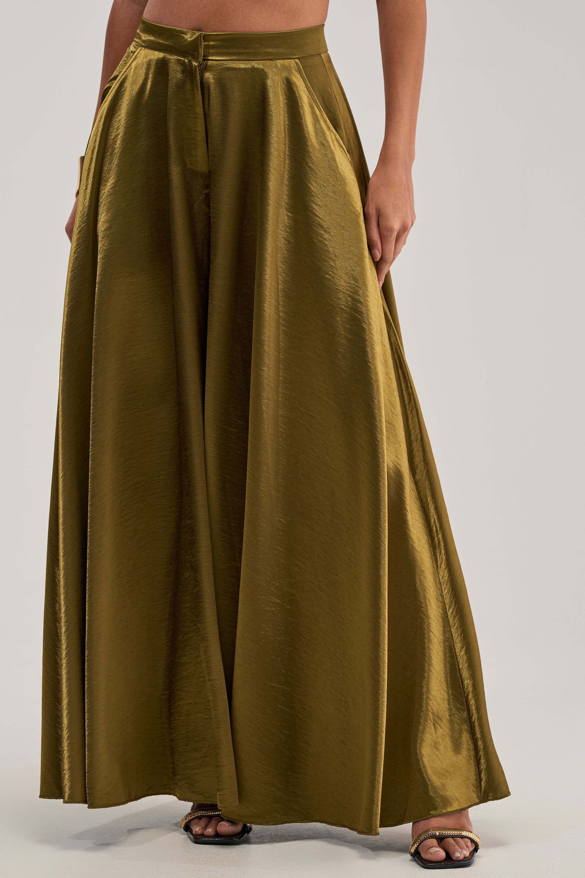 Wearing the TRUE GODDESS GREEN PALAZZO PANT, featuring a high-rise waist and wide-leg silhouette, paired with open-toed heels, the person stands against a plain light background.