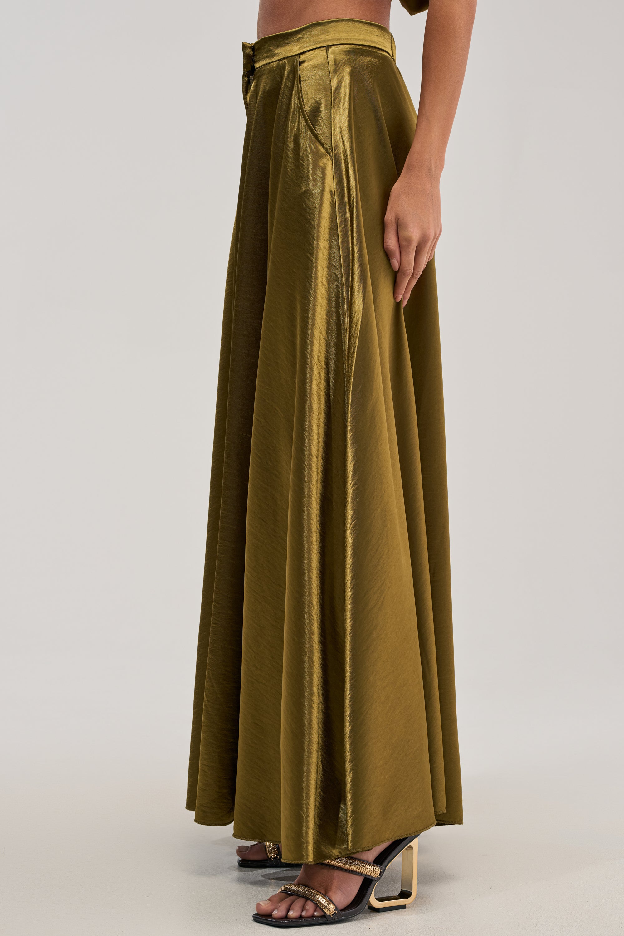 A person wears the TRUE GODDESS GREEN PALAZZO PANT, featuring pleats and a high-rise waist, styled with black open-toe heeled sandals against a plain light background.