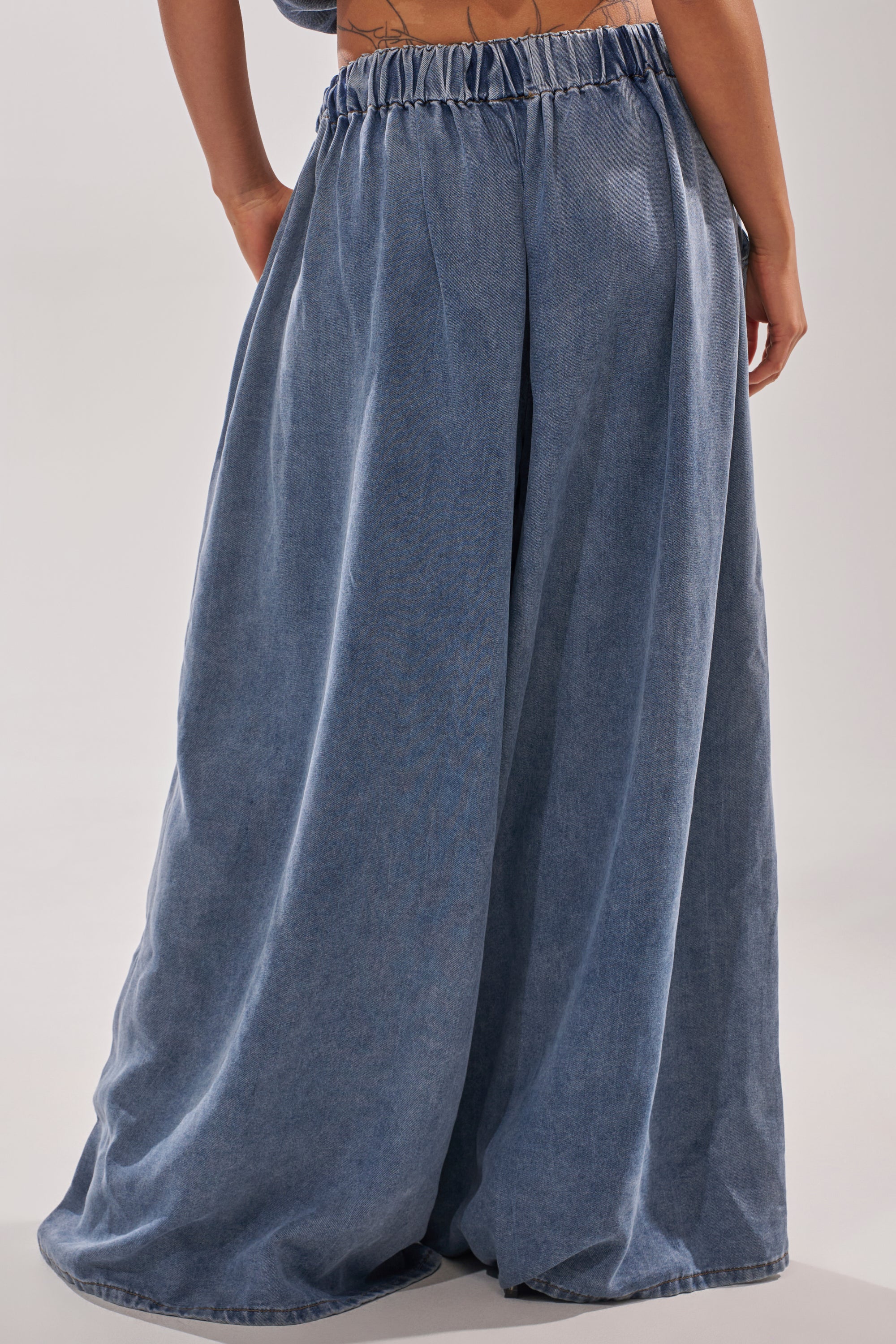 Someone wears the DENIM FOR DAYS JOGGER, featuring a high-rise elastic waistband. These wide-leg, loose-fitting denim pants are shown from behind, capturing only the waist down. 4