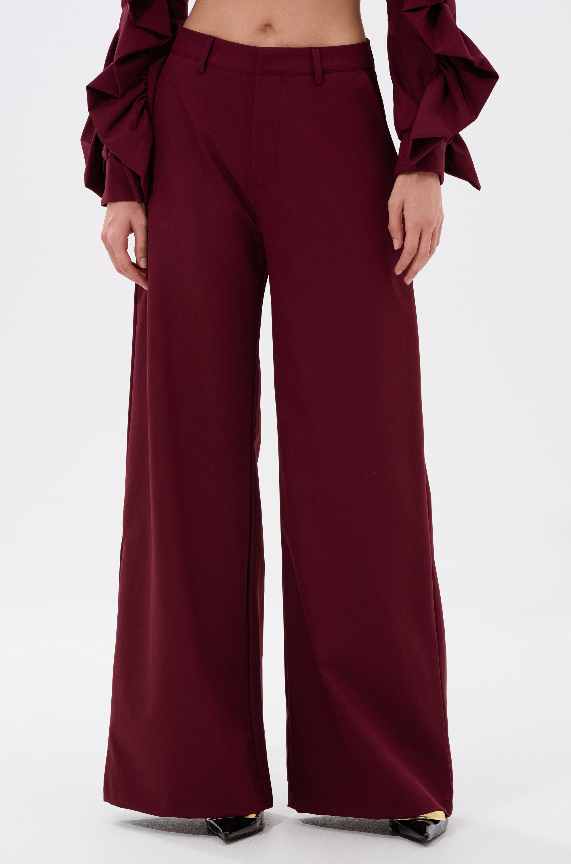 Someone wears the high-waisted, wide-leg SIERRA TROUSER with a matching ruffled-sleeve top, standing against a plain white background. 1
