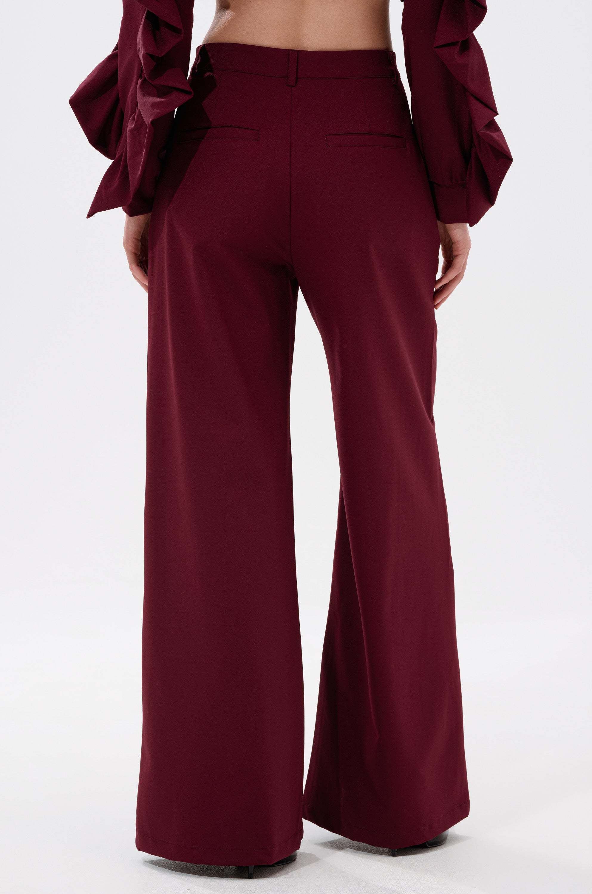 Someone wearing the SIERRA TROUSER, featuring a high-rise fit and red wide-leg design. 3