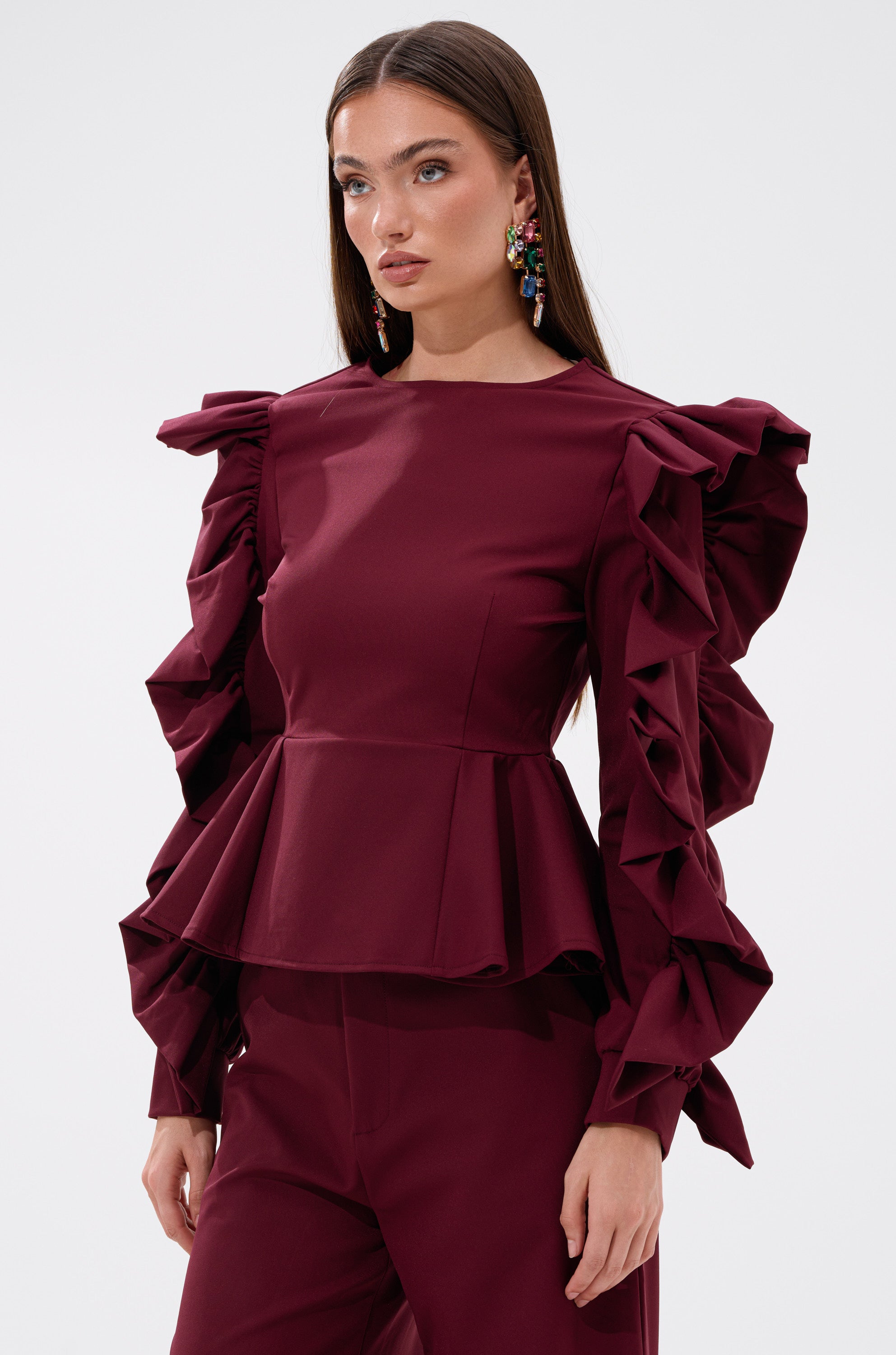 A woman in the SIERRA RUFFLE BLOUSE, featuring dramatic ruffles and a peplum hem. 0