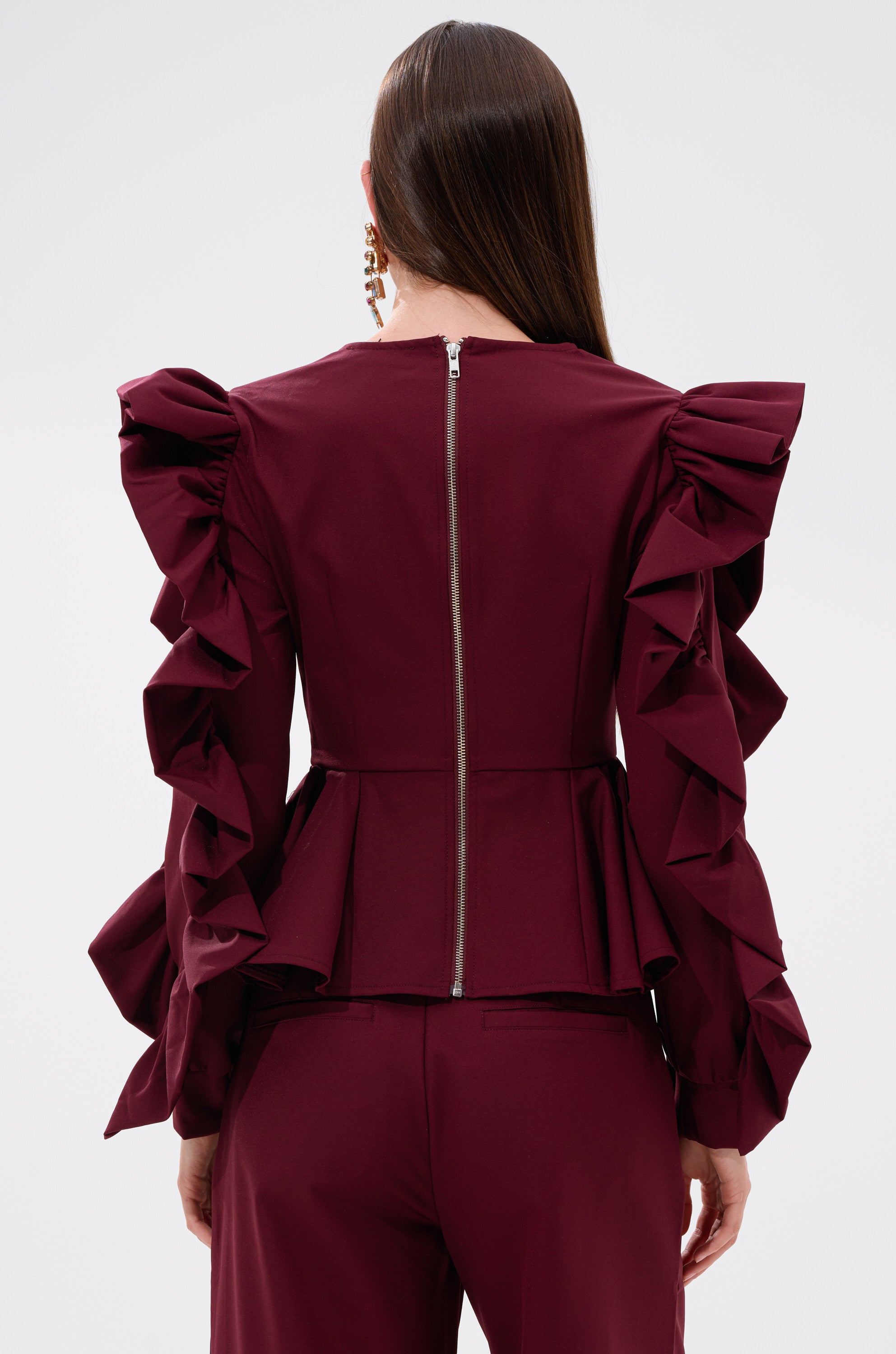 A woman wears the SIERRA RUFFLE BLOUSE, featuring cascading ruffles, paired with matching pants. 3