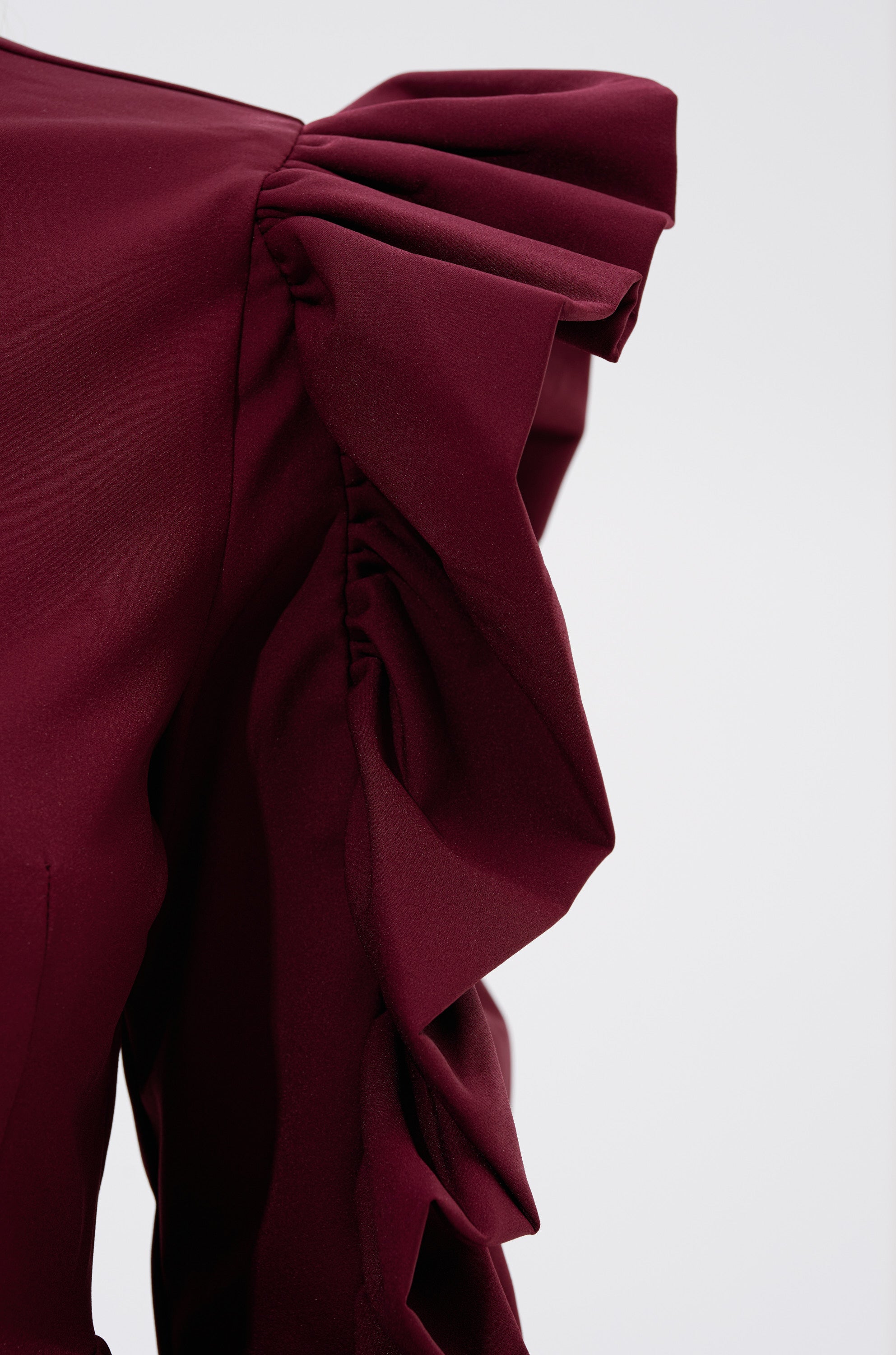 A close-up of the SIERRA RUFFLE BLOUSE in vibrant red, showcasing cascading ruffles that add dramatic texture and movement to its elegant design. 6