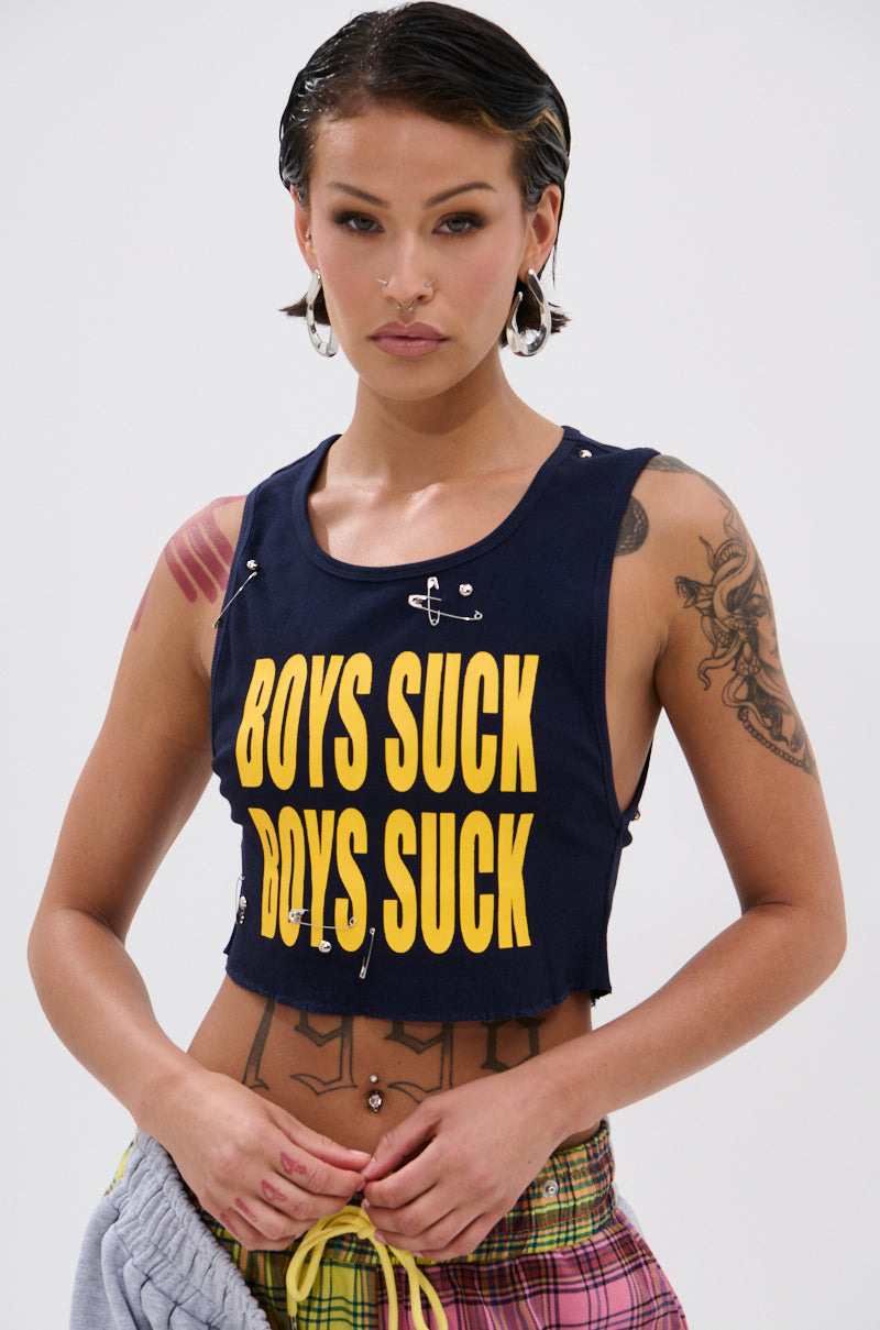 A woman with tattoos and piercings channels punk style in the BOYS LIE Distressed Cropped Tank Top, featuring bold yellow "BOYS SUCK" text, paired with slicked-back hair against a plain background. 0