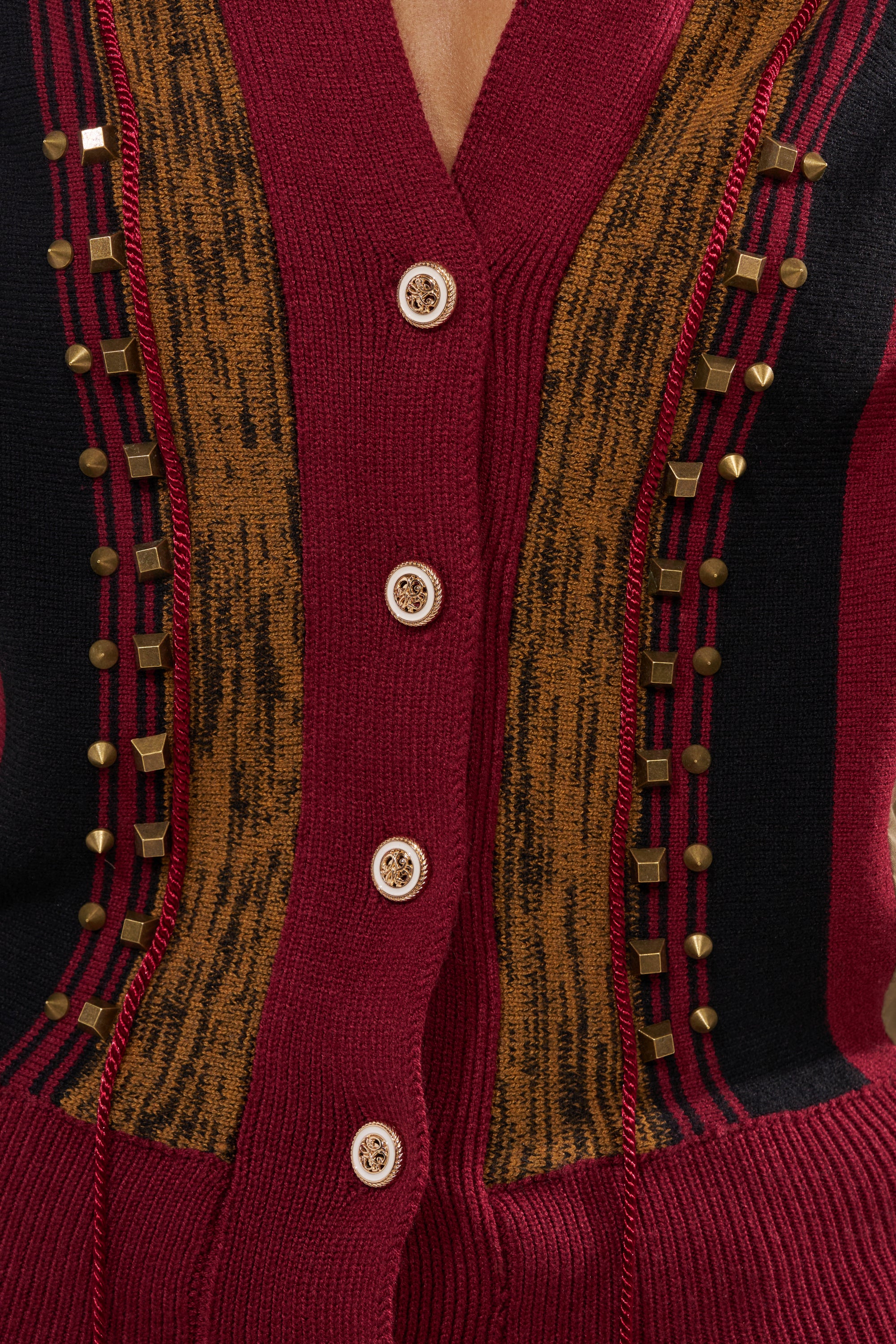 Close-up of the NEW DAY COLORBLOCK CARDIGAN—red with brown and black vertical patterns, gold buttons, and small square gold studs in vertical rows beside the button placket. 9