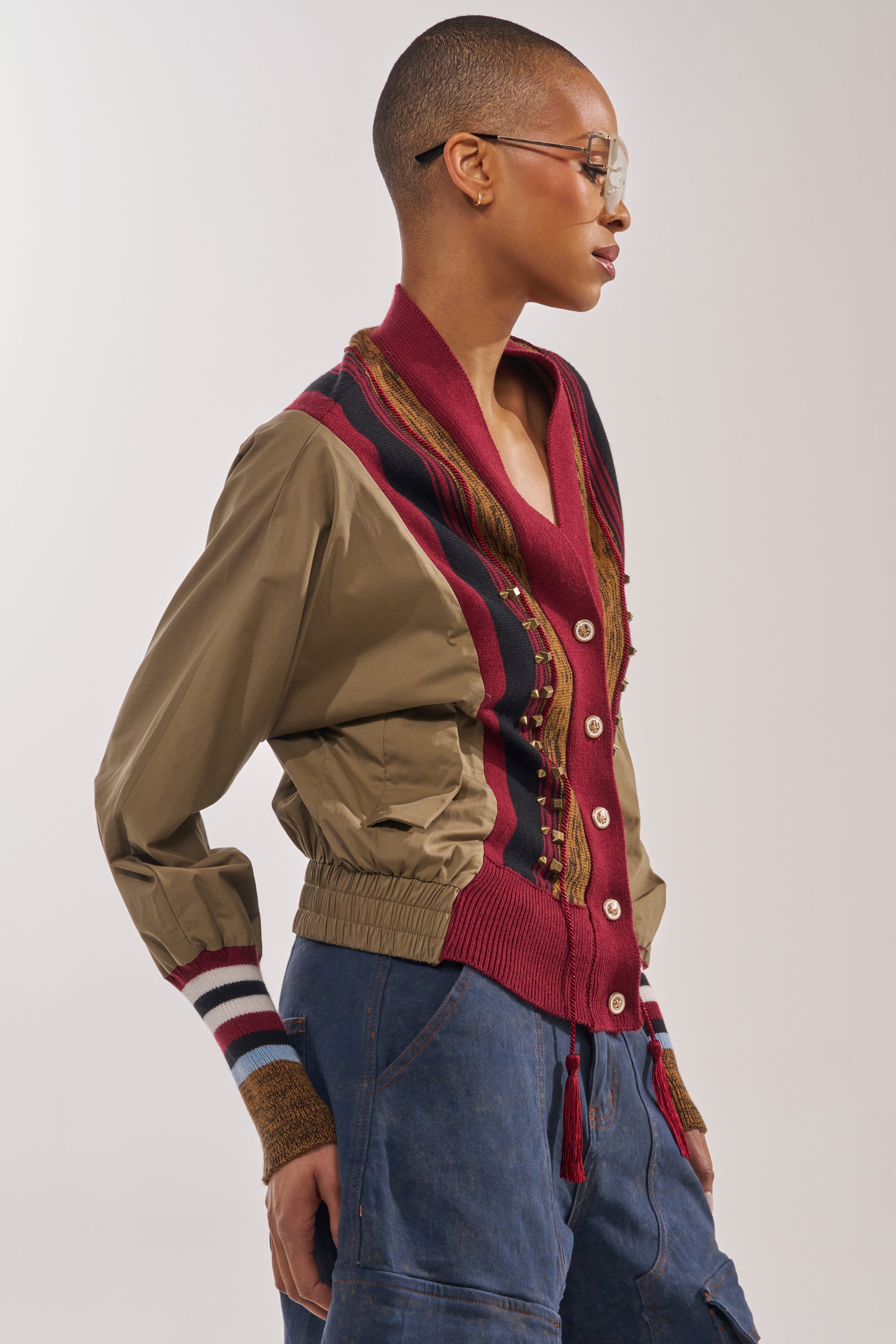 A person with short hair and glasses stands in profile against a neutral background, wearing the NEW DAY COLORBLOCK CARDIGAN with a red collar, khaki sleeves, and blue pants. 3