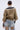 A person with hair in a bun wears the BEAUTIFUL DAY CARDIGAN, featuring tan color-blocking and striped cuffs and collar, paired with light blue distressed jeans. The photo is taken from behind against a plain background.