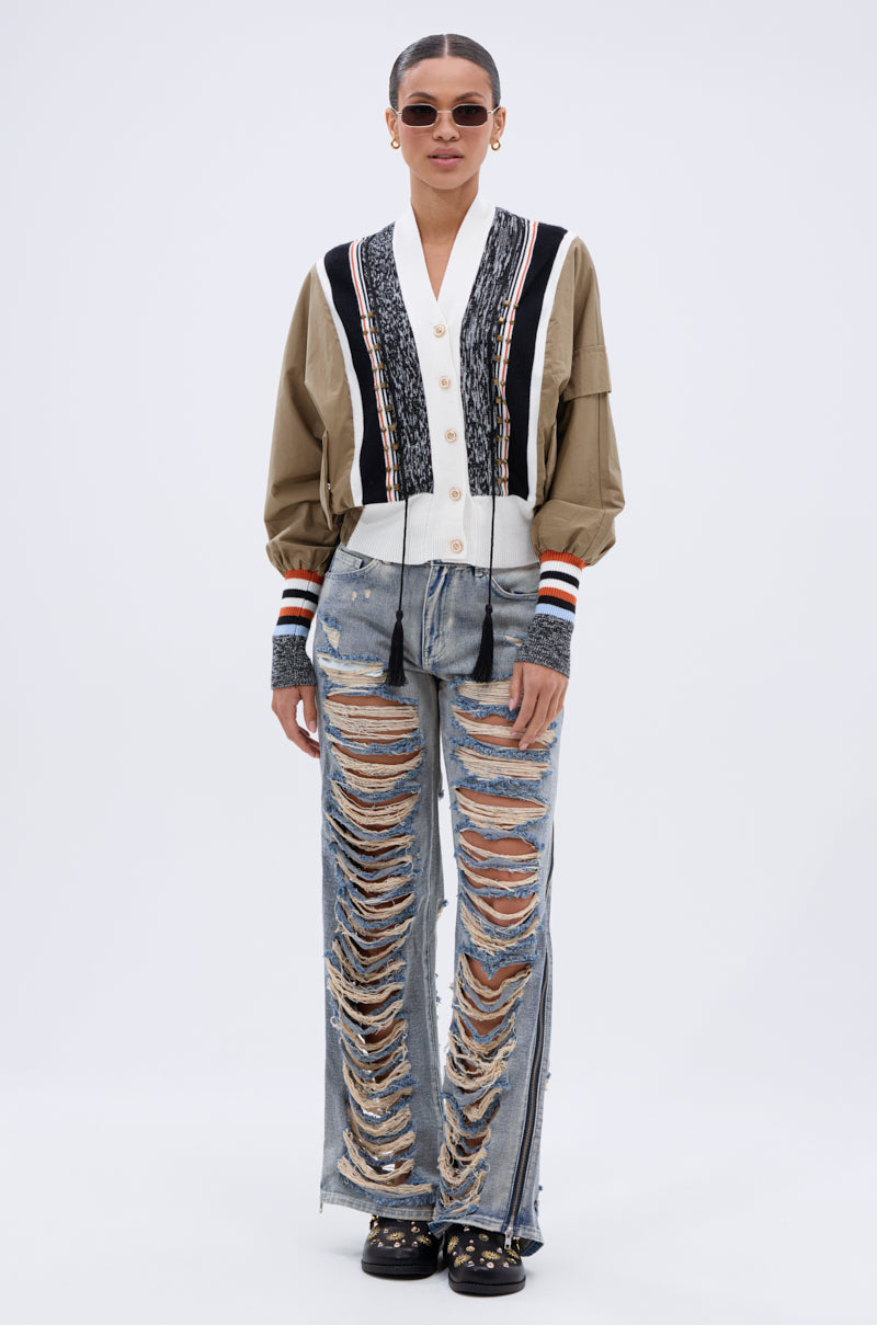 A person wearing sunglasses, heavily distressed blue jeans, and the BEAUTIFUL DAY CARDIGAN with white and orange trim stands facing forward against a plain white background.