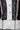 Close-up of the BEAUTIFUL DAY CARDIGAN, a color-blocked knit with black, white, and patterned panels, six beige buttons, gold square studs, red and white placket stripes. Blue denim jeans are also seen at the bottom.