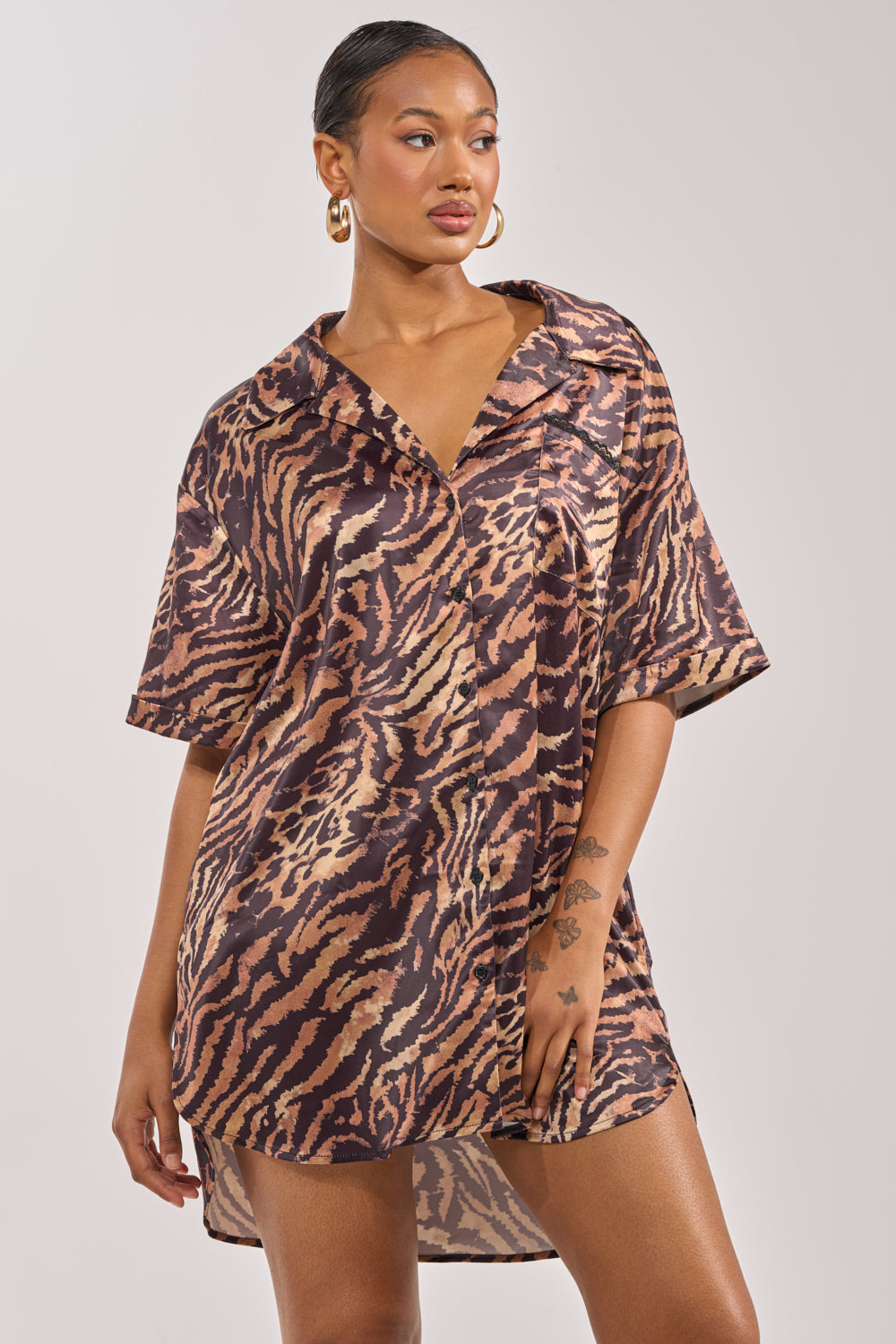 A woman models the DON'T MAKE A SOUND PRINTED MINI DRESS IN TIGER with black lace trim and loose short sleeves, standing against a plain background, looking to the side. 1
