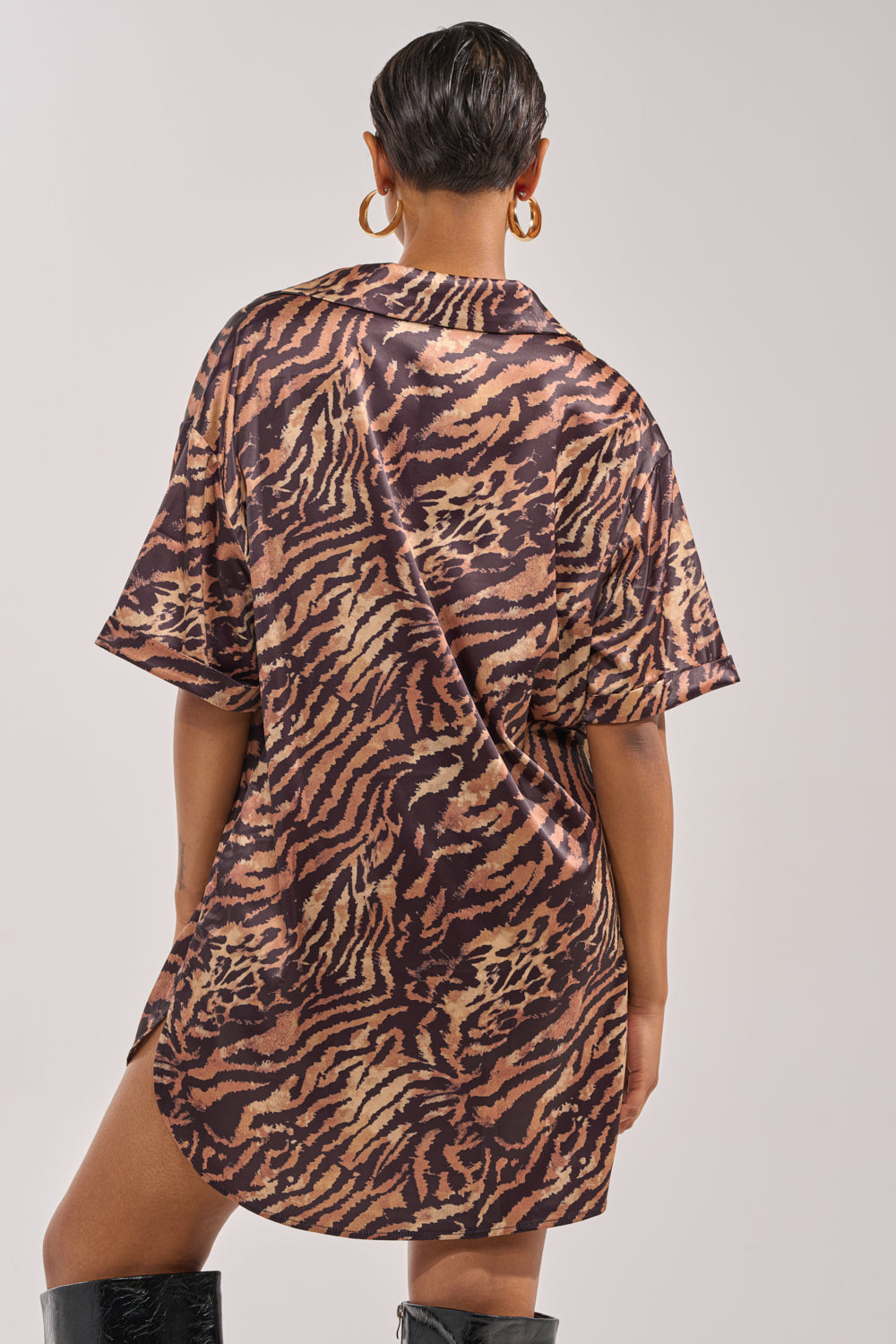 A person with short hair is shown from the back wearing the DON'T MAKE A SOUND PRINTED MINI DRESS IN TIGER, styled with large gold hoop earrings and black knee-high boots. 3