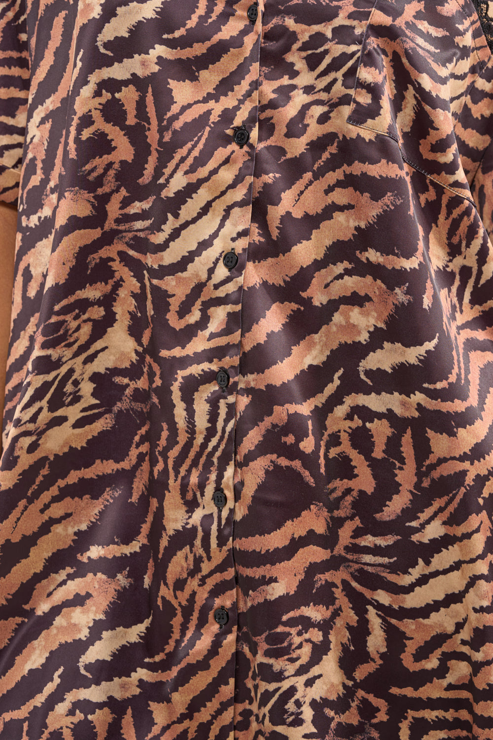 Close-up of the DON'T MAKE A SOUND PRINTED MINI DRESS IN TIGER—a satin mini shirt dress with a tiger stripe pattern in brown, tan, and black, and sleek black buttons down the center. 5