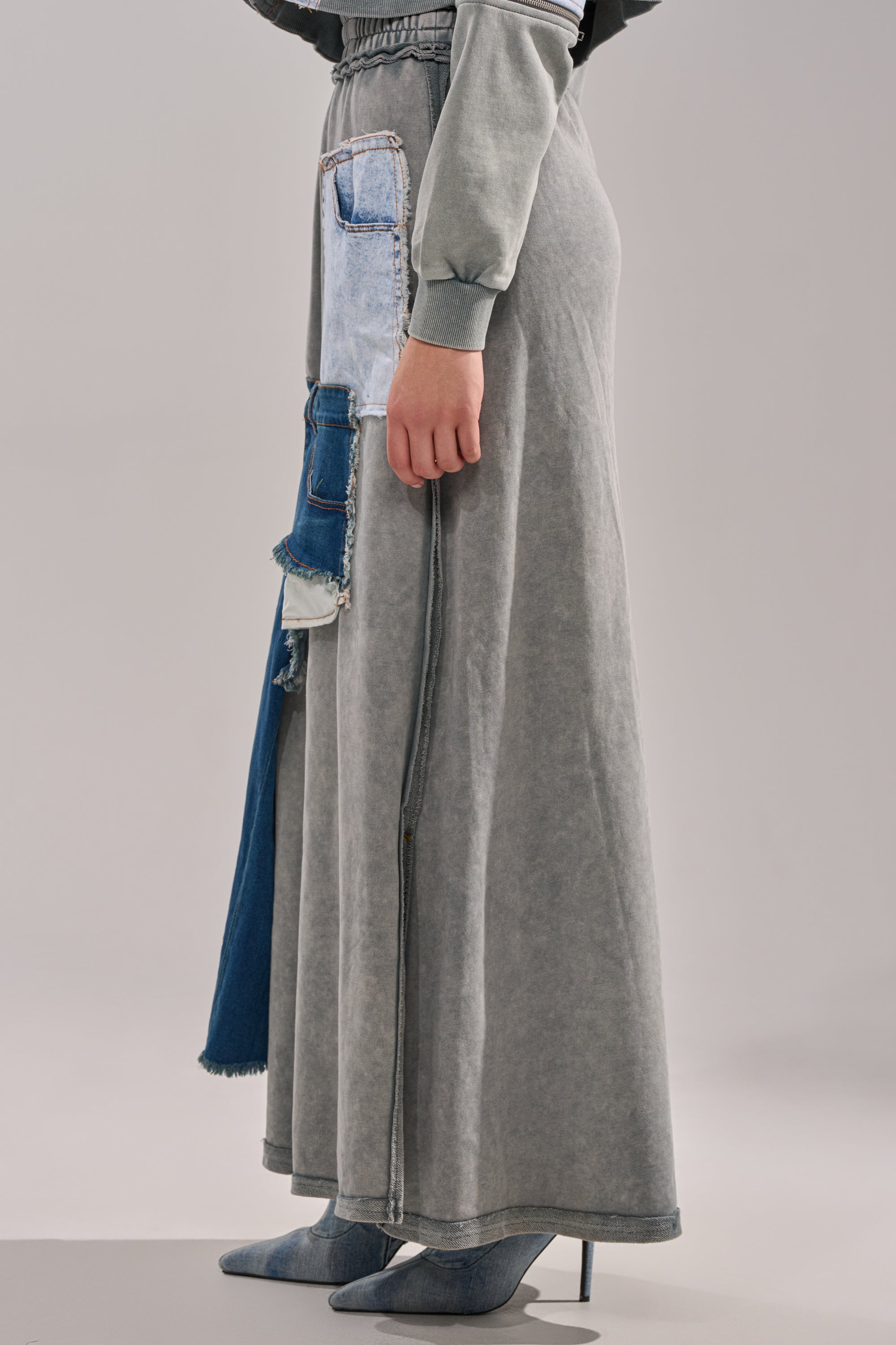 Someone wears the DENIM DREAMS ZIPPER DETAIL MAXI SKIRT with an elastic waistband and front slit, styled with heeled pointed-toe boots against a plain light-colored background.