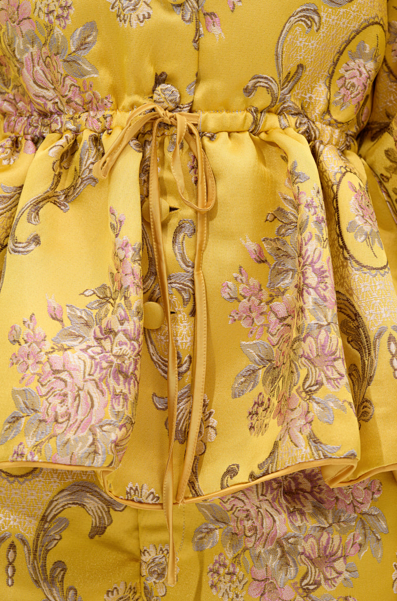The ETHEREAL BROCADE SHORT SLEEVE BLOUSE features yellow satin brocade with a vintage-inspired pink and gold floral pattern, a drawstring bow at the waist, and an embroidered, shiny finish for an elegant look.