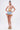 A woman stands against a plain background wearing the VIVI FLORAL DENIM SHORT with embroidered floral appliques and a ruffled hem, paired with a strapless floral corset top, rainbow-striped platform heels, and large hoop earrings.