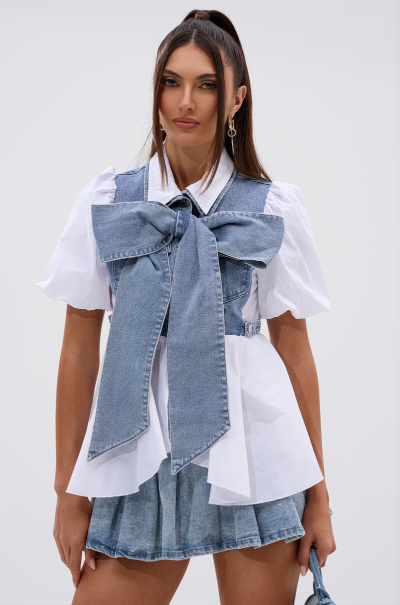 A woman wears the FAITH SHORT SLEEVE DENIM TIE POPLIN BLOUSE TOP with a matching denim vest and short skirt, styled in front of a plain light background. 2