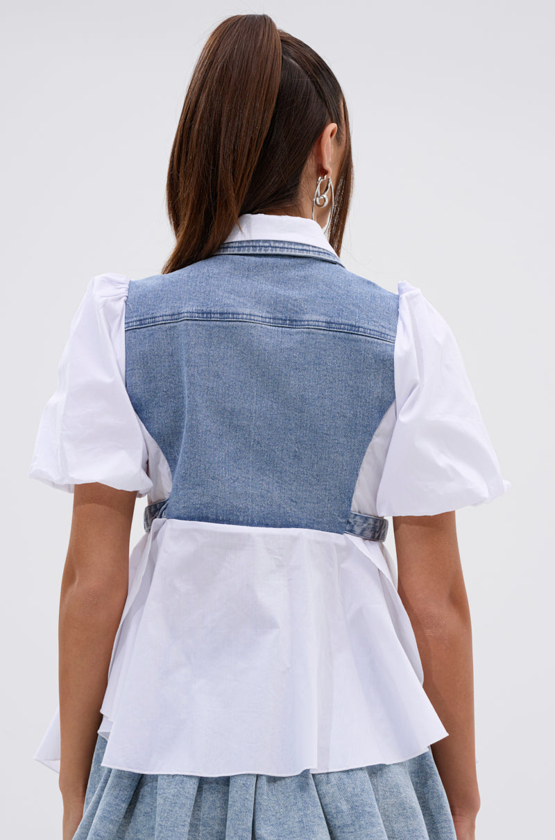 A woman with long brown hair in a high ponytail is seen from the back, wearing the FAITH SHORT SLEEVE DENIM TIE POPLIN BLOUSE TOP paired with a blue denim vest and a matching light blue pleated skirt. 4