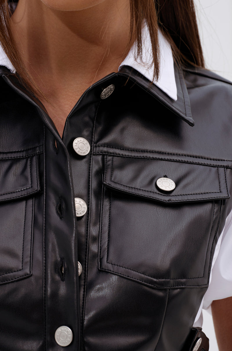Close-up of a woman wearing the NEW DRESS CODE LEATHER AND POPLIN BUTTON DOWN SHIRT, featuring black faux leather with silver buttons over a white collar. The focus highlights the garment’s upper chest, collar area, and button details. 7