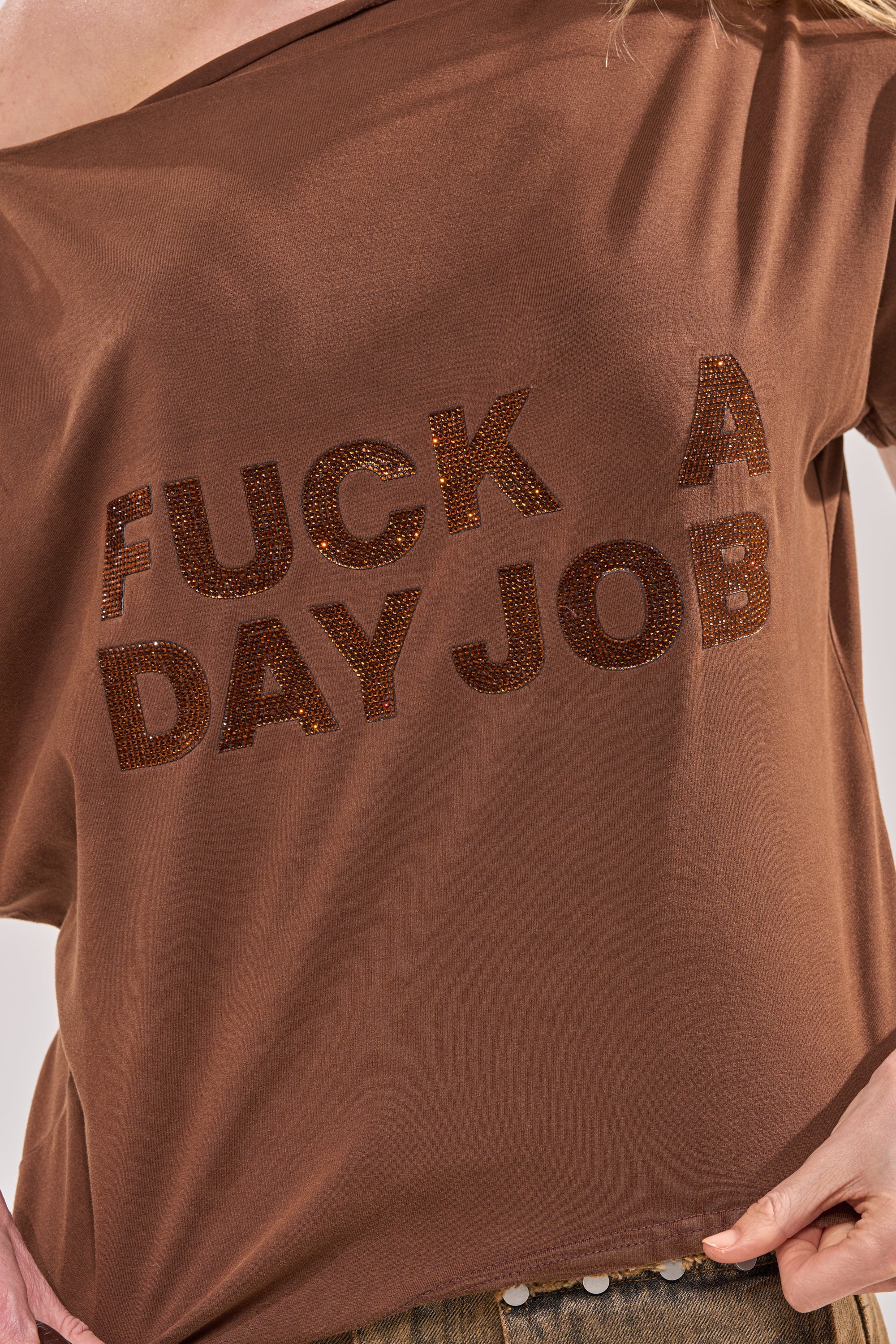 Wearing the FCK A DAY JOB OFF THE SHOULDER BROWN TEE—a slouched, cotton streetwear piece with bold sequined text—creates an effortlessly edgy festival look. 11