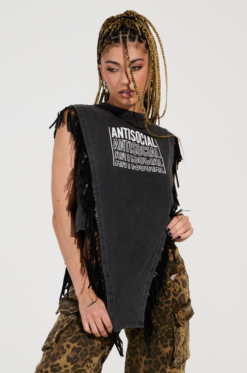 A person with braided hair is wearing the ANTISOCIAL FRINGE DETAIL TSHIRT, a sleeveless black top repeatedly printed with "ANTISOCIAL," as they stand against a plain background. Their leopard print pants and the edgy vibe of their look, highlighted by faux leather fringe details, make for a striking fashion statement.