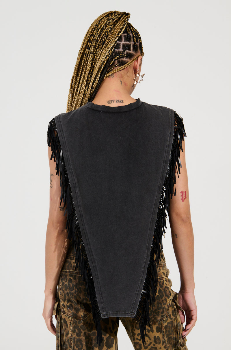 A person with braided hair is wearing an ANTISOCIAL FRINGE DETAIL TSHIRT showcasing a sleek triangular back design. Tattoos cover their arms and neck, and they have paired it with patterned pants. The minimalist backdrop allows their style to shine effortlessly.