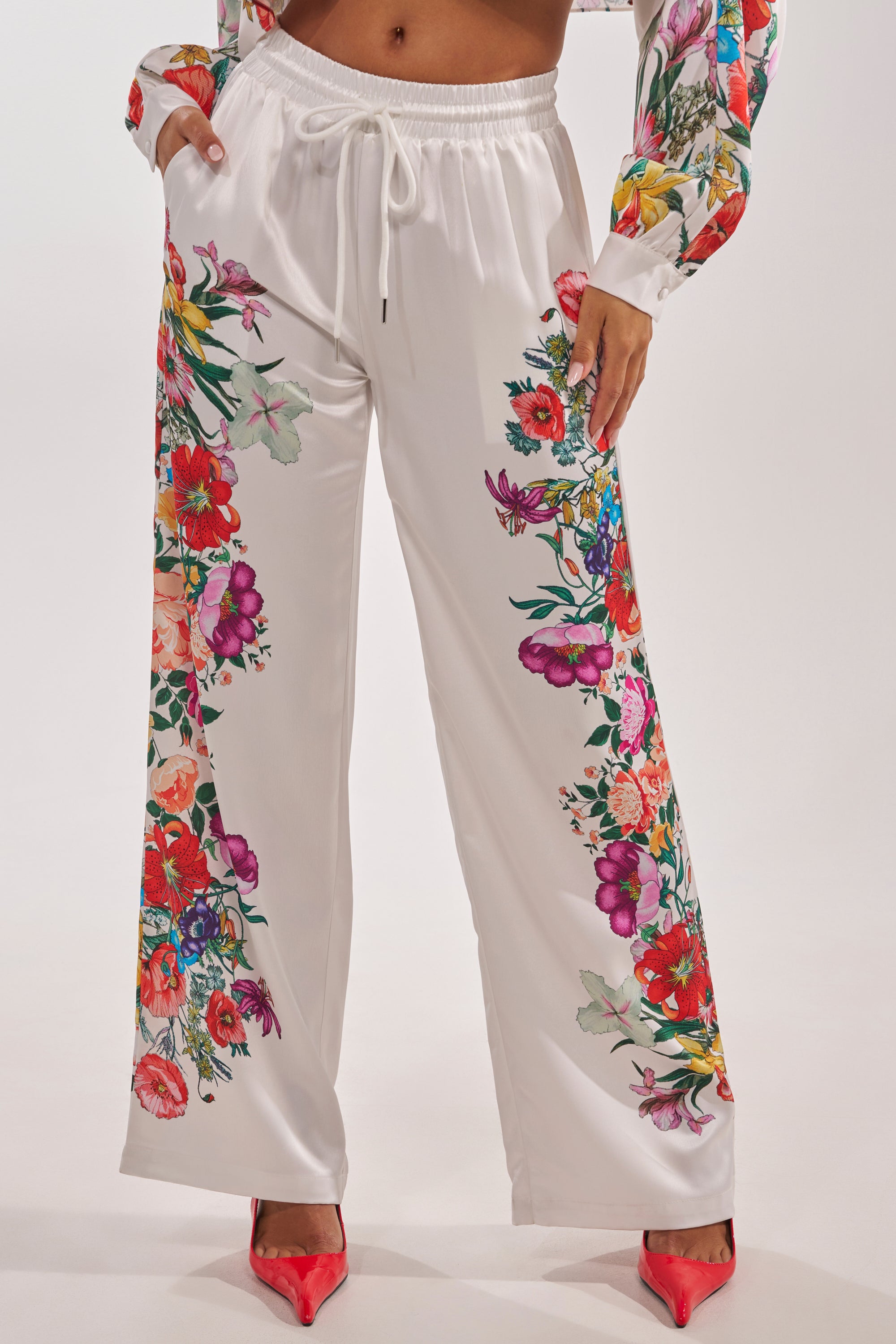 Wearing the FULL BLOOM STRAIGHT LEG TROUSERS with a vibrant floral motif, paired with a matching top and red pointed-toe heels, creates a chic spring ensemble. 3