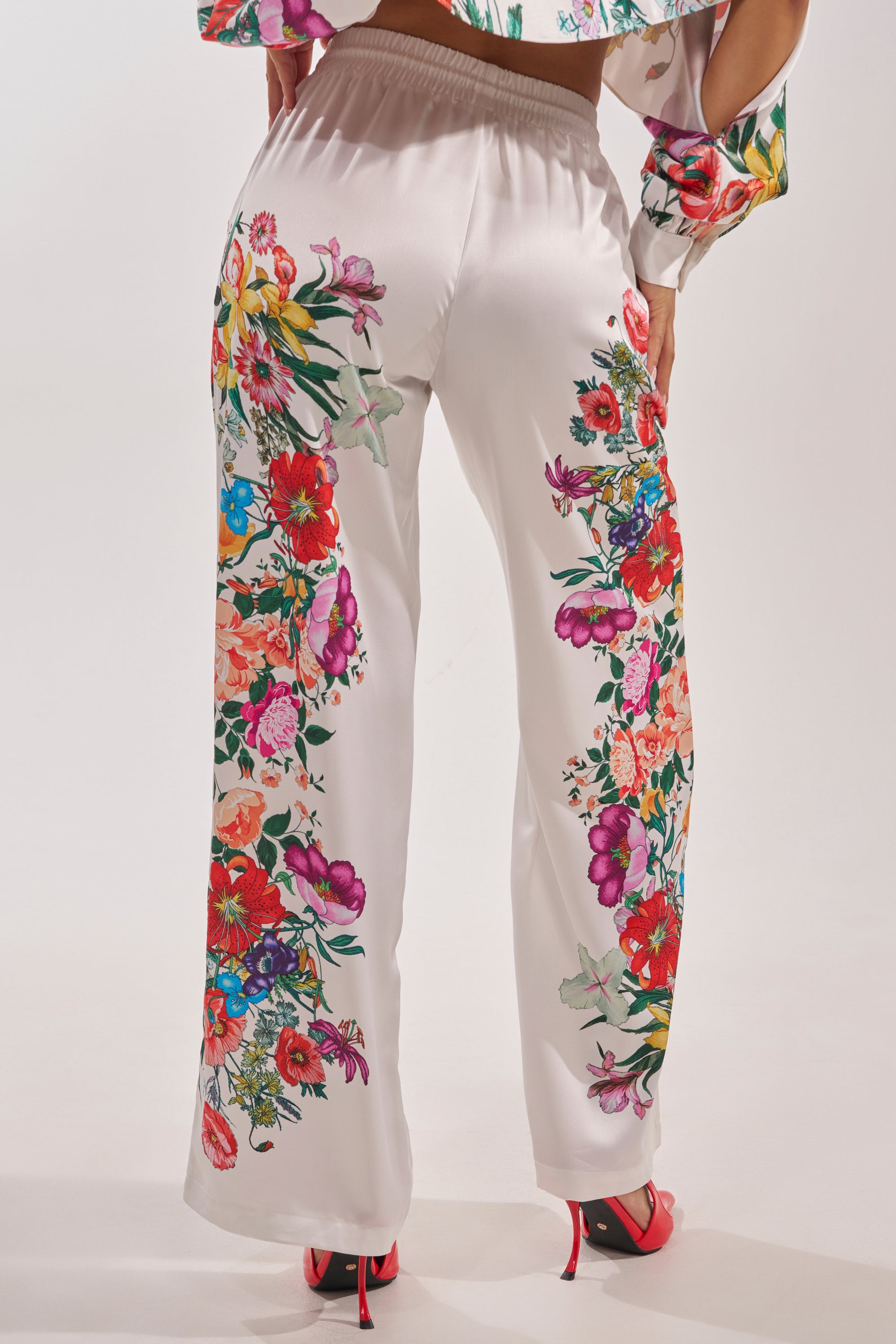 A person shown from the back wearing FULL BLOOM STRAIGHT LEG TROUSERS with colorful floral side prints and matching heels, set against a plain background—ideal for a chic spring look. 6