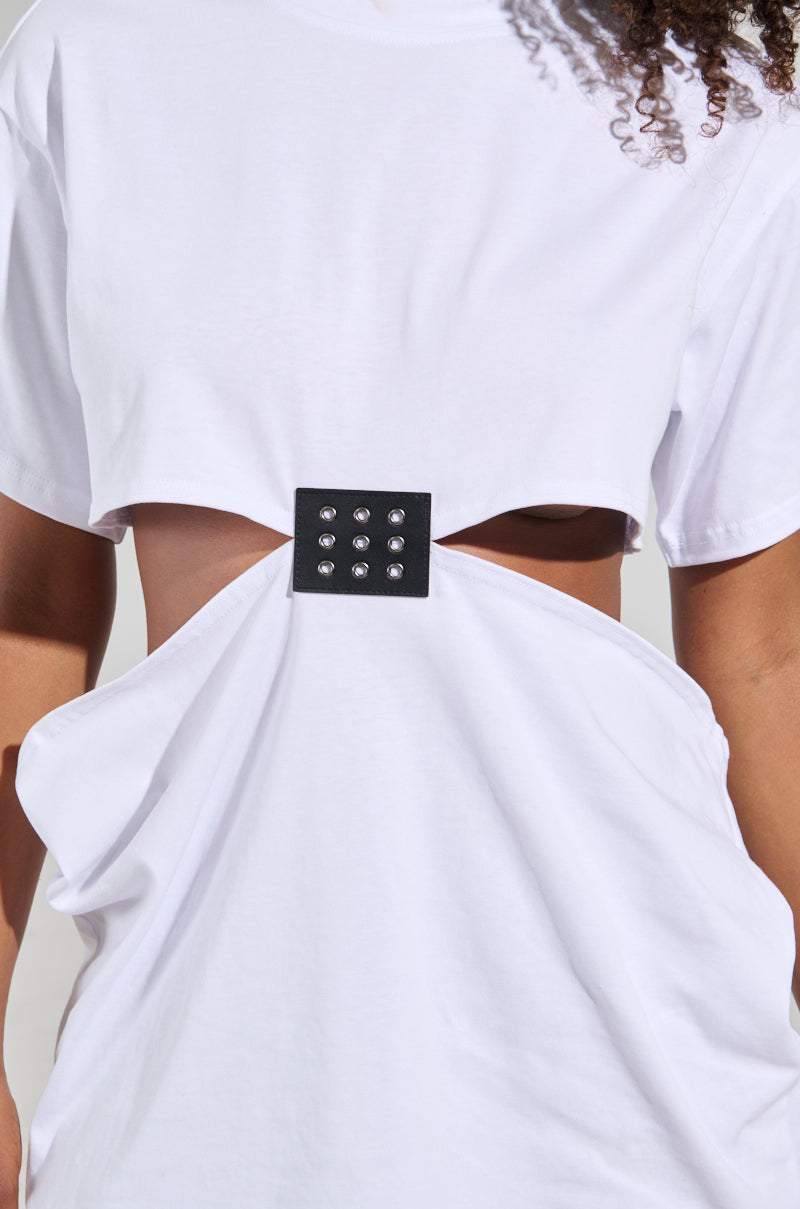 A close-up of a person wearing the GIRL BOSS MOMENTS CUT OUT T-SHIRT, showcasing its distinctive design. The white shirt is accented with a black square patch at the center, adorned with decorative metallic studs that emphasize its stylish detail.