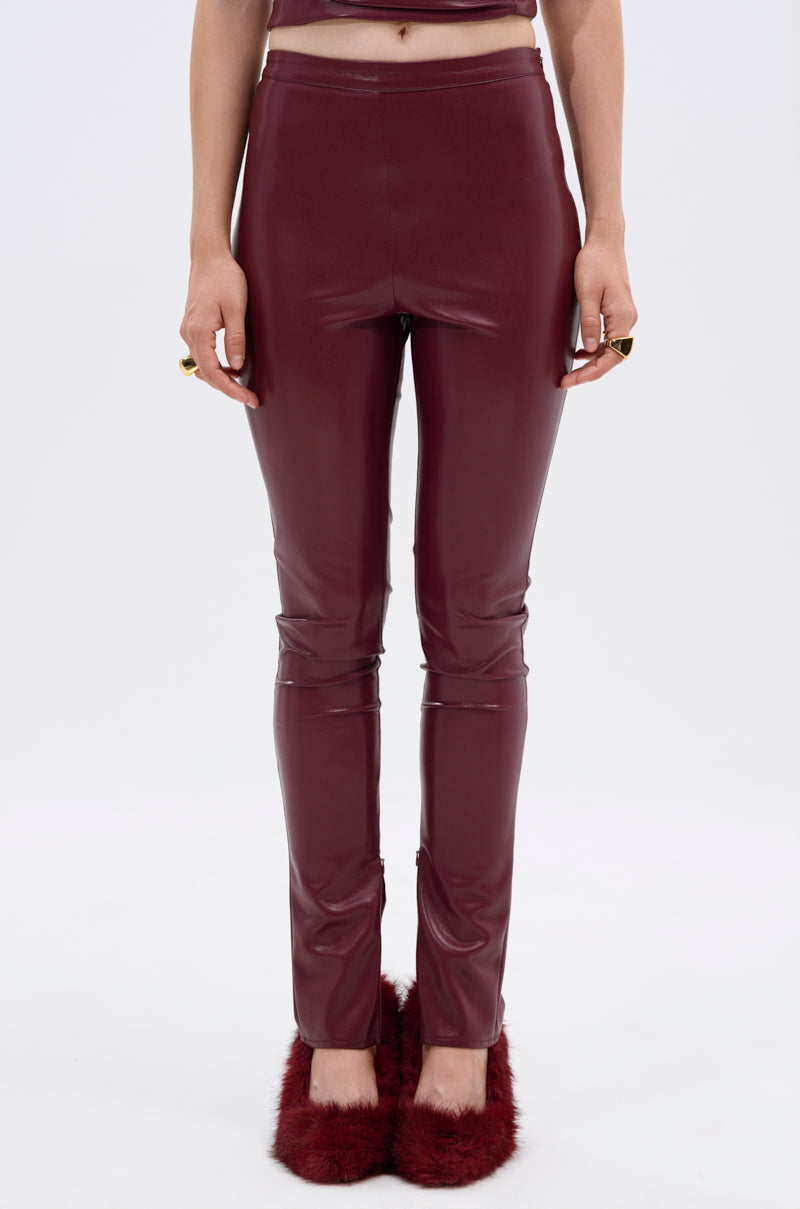 A person stands against a plain white background, wearing FIRE SQUAD BURGUNDY LEGGING—high-waisted, tight-fitting faux leather leggings—with maroon furry slippers and hands relaxed at their sides. 4