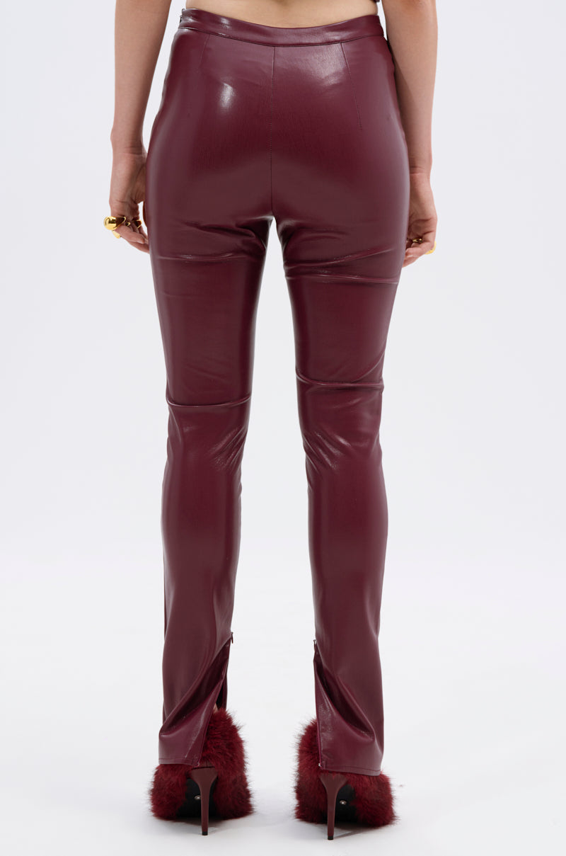 A person stands facing away, wearing FIRE SQUAD BURGUNDY LEGGING—high-rise, curve-hugging faux leather—and high-heeled shoes with burgundy fur accents, set against a plain light background. 6