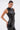 A woman with slicked-back hair and large hoop earrings poses confidently in the STRAIGHT TO THE POINT FAUX LEATHER BLOUSE, featuring a sleeveless design with a mock neckline, paired with matching pants against a plain light background.