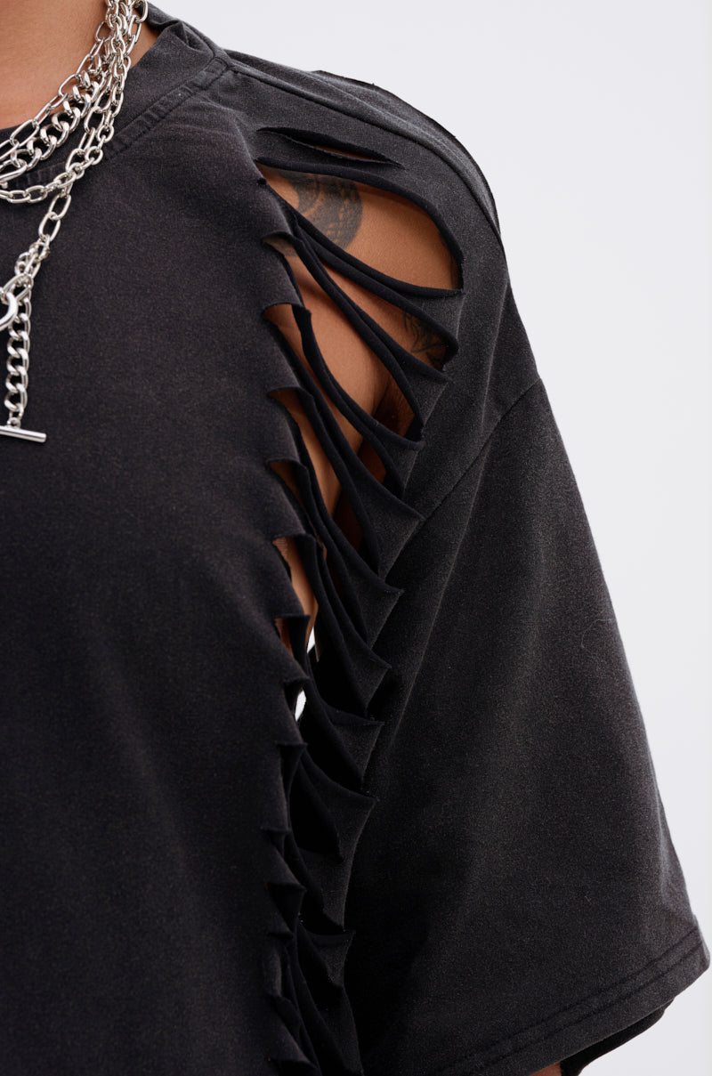 Close-up of a person wearing the SHAINA DISTRESSED OVERSIZED TEE featuring slashed cut-out details on the shoulder and sleeve, paired with layered silver chain necklaces. 7