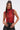 Woman with long brown hair in a high ponytail wears the SEXY LITTLE SNAKE MESH TOP IN RED, paired with black leather pants, large hoop earrings, and a silver chain necklace, standing against a plain light background.