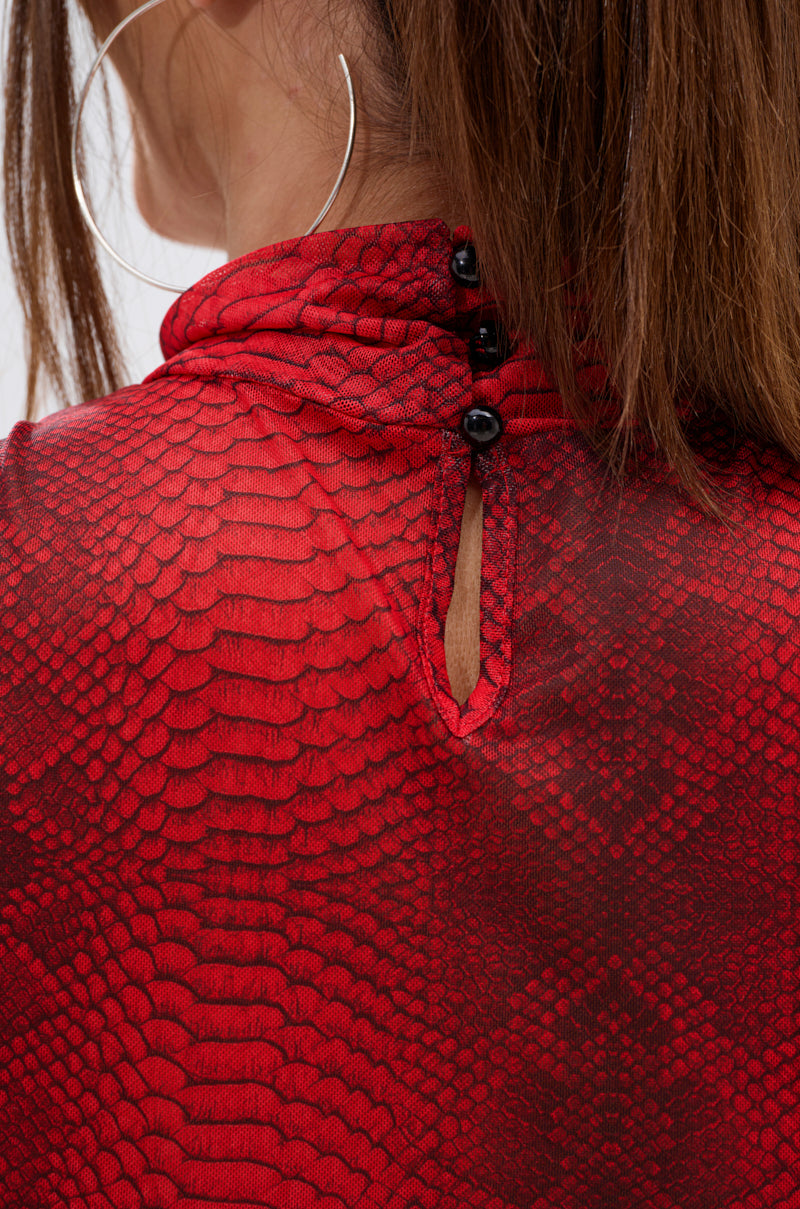 Close-up of a woman’s neck and shoulder wearing the SEXY LITTLE SNAKE MESH TOP IN RED, featuring black back buttons. She has straight brown hair and large silver hoop earrings. 7