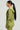 A person with long black hair is shown in profile, featuring a relaxed-fit light green IN MY ELEMENT HOODIE paired with matching pants, set against a plain gray background that highlights the cozy cotton fabric.