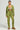 A person stands against a neutral background wearing the light green IN MY ELEMENT HOODIE and relaxed-fit drawstring pants. They are sporting brown heeled shoes with their hair pulled back, facing forward with a neutral expression that effortlessly embodies the vibe of the hoodie.