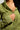 A person is wearing an olive green IN MY ELEMENT HOODIE, partially unzipped to show a hint of skin. They hold the zipper with one hand, highlighting the cotton hoodie’s relaxed fit and visible drawstrings.