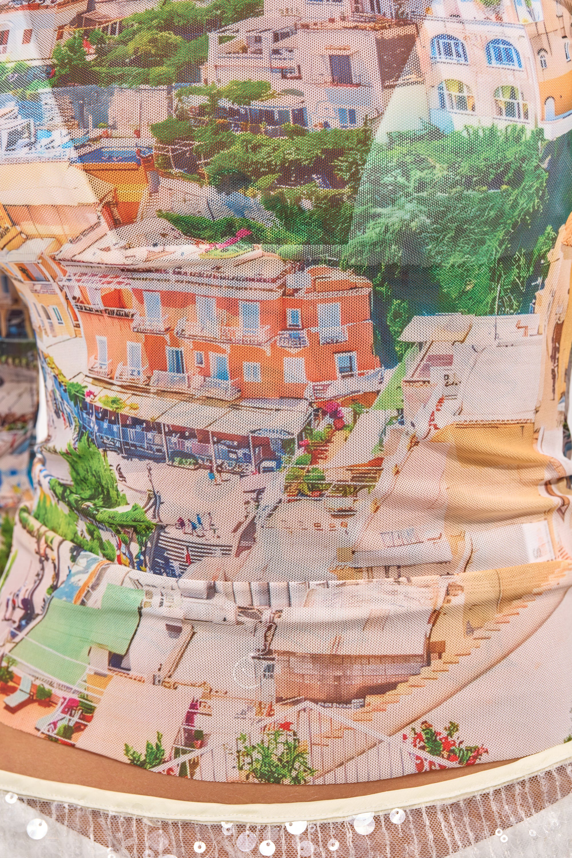 Close-up of the AMALFI DAYS MESH TOP, showcasing a vibrant Amalfi cityscape print with Mediterranean buildings, lush greenery, and scenic steps—ideal for standout streetwear style. 7