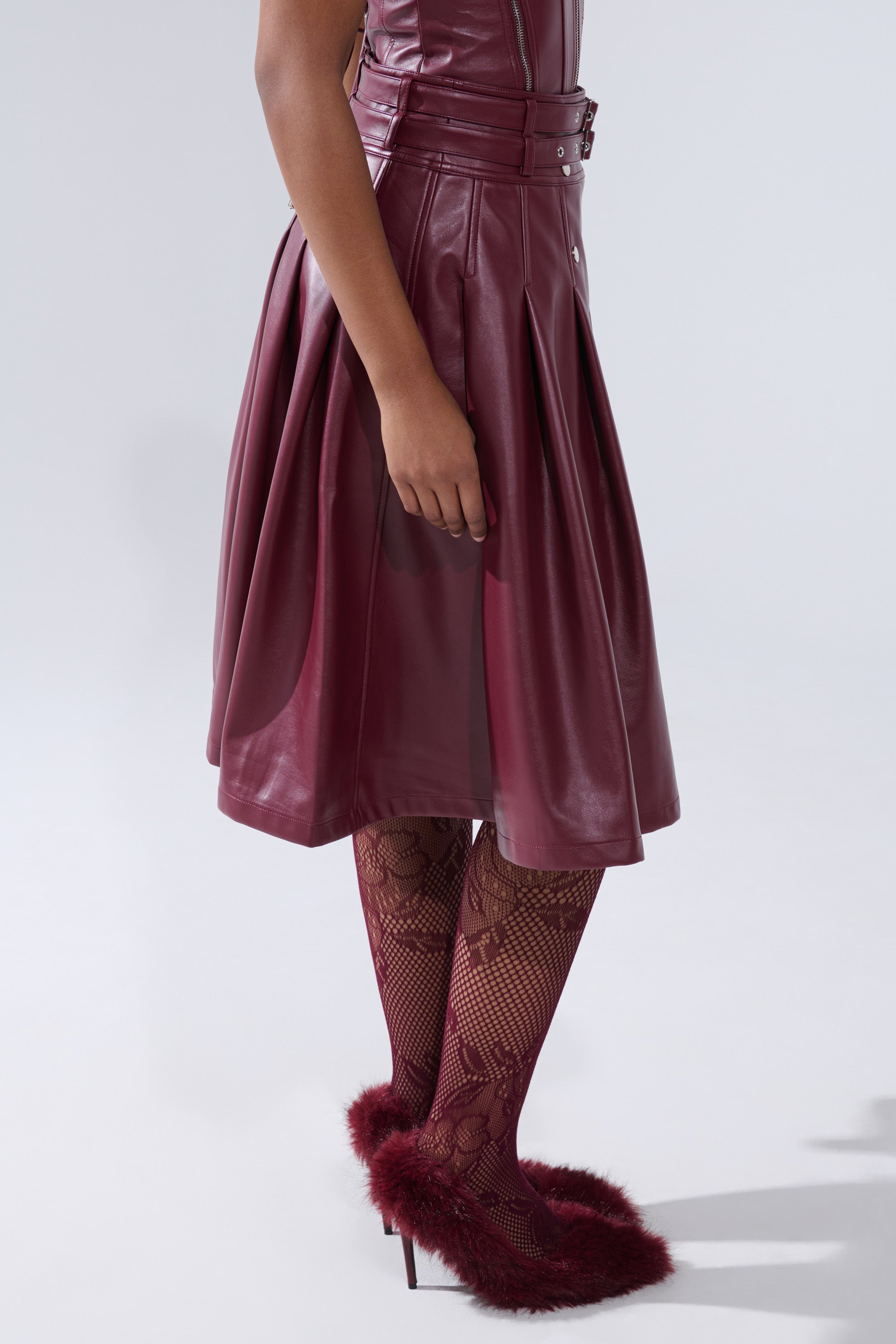Wearing the FEELING THE ENERGY MIDI SKIRT as a sleeveless dress, paired with burgundy lace tights and marabou-trimmed burgundy heels, a person poses against a plain light background.