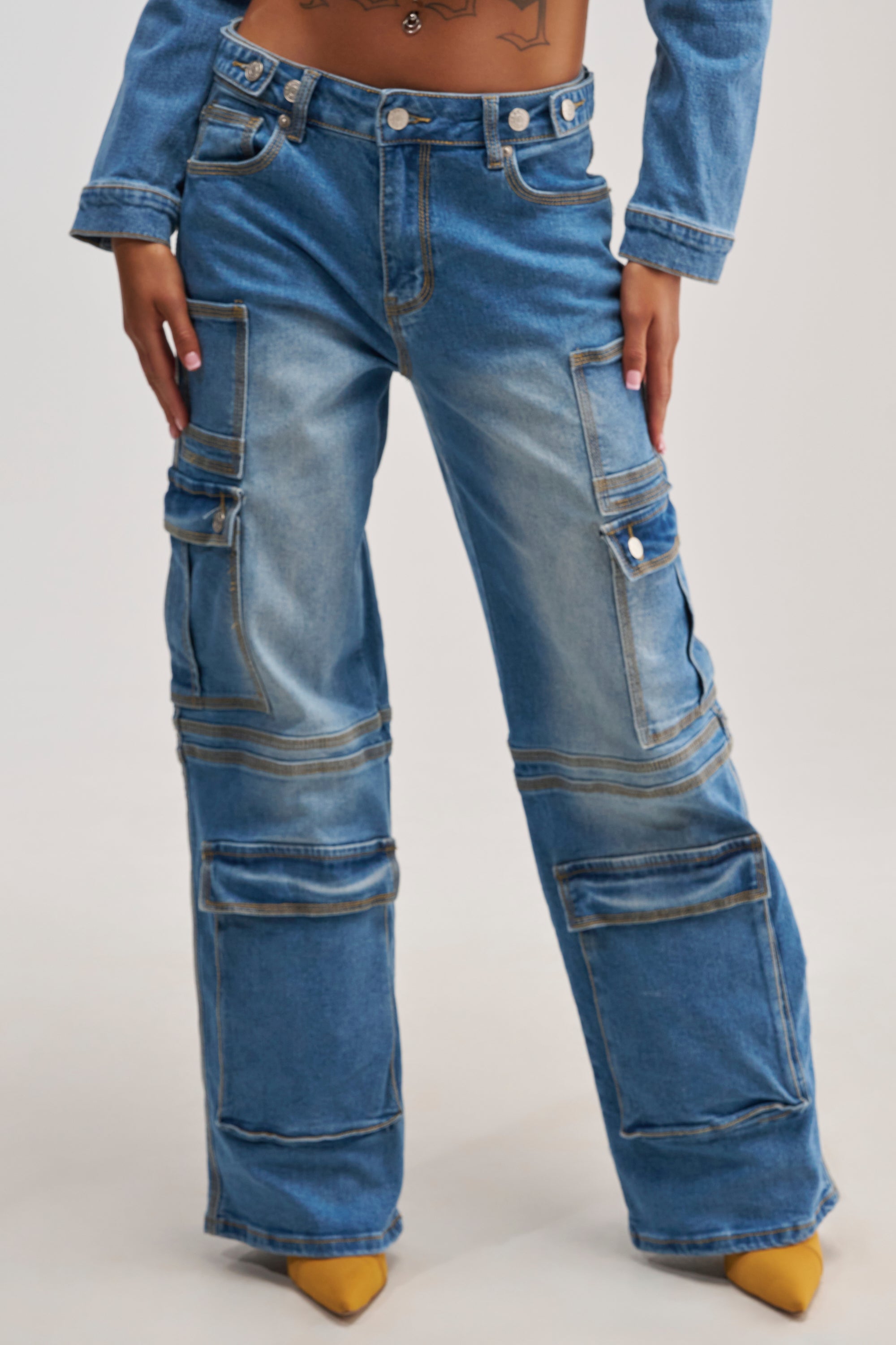 Wearing the DENIM FOR DAYS CARGO DENIM, this person showcases blue wide-leg jeans with multiple oversized pockets, paired with yellow pointed-toe shoes. The cropped photo—from torso to feet—focuses on the relaxed streetwear vibe of these standout cargo jeans.