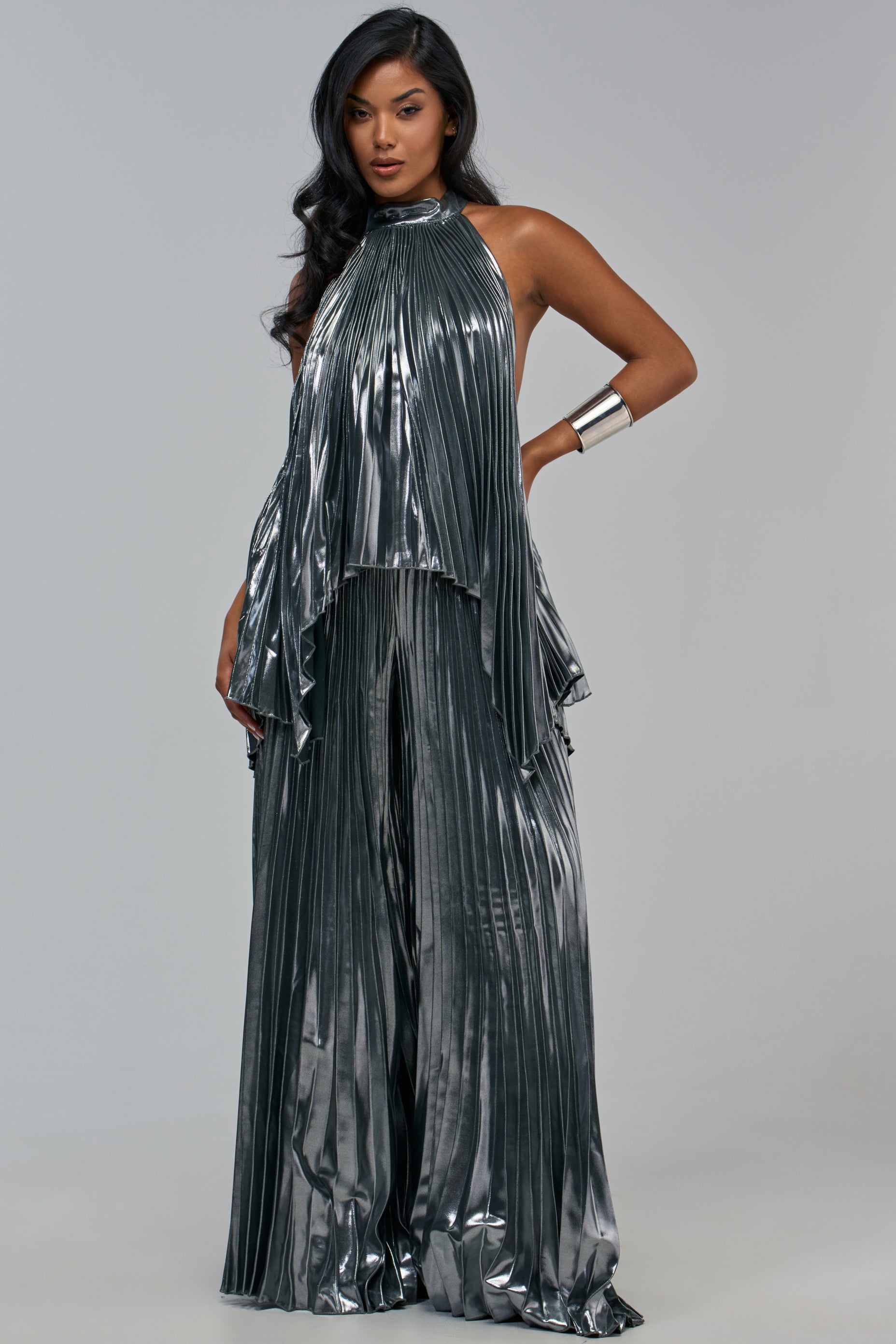 A person wearing a metallic silver, sleeveless, pleated halter top paired with matching ALL EYES ON ME PLEATED PANT for luxe styling.