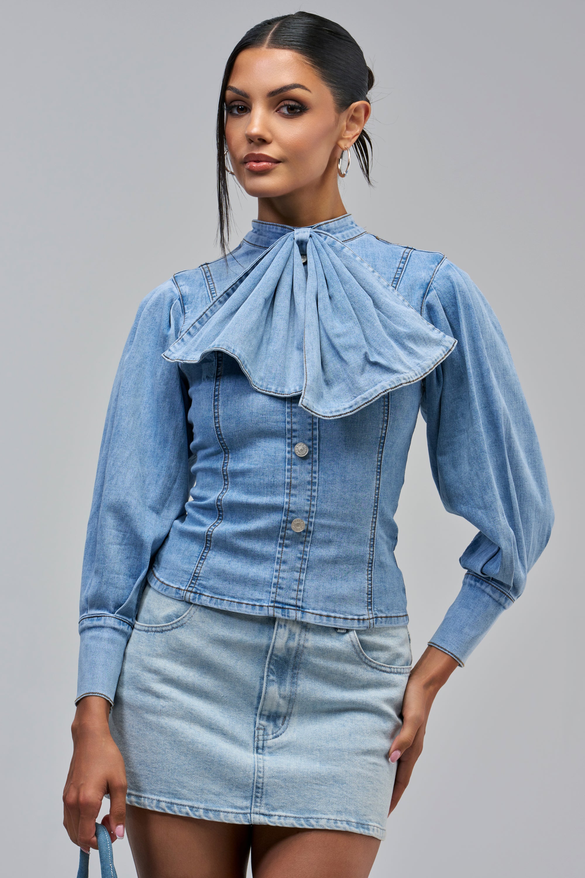 JESSIE DENIM BLOUSE, a long-sleeved light wash denim bow blouse featuring a large bowtie collar and front button closure.