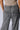 A person is wearing the DONT STOP MOVIN TROUSER by AKIRA, featuring grey, acid-washed, high-waist wide-leg trousers with two back pockets. They have one hand partially in a pocket and are sporting a light-colored, cropped short-sleeve top. The background is plain and light-colored.