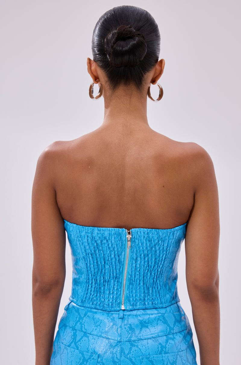 A woman with her hair in a bun is seen from the back wearing the strapless, textured blue ELECTRIC SNAKE CORSET with a visible center zipper and large hoop earrings.