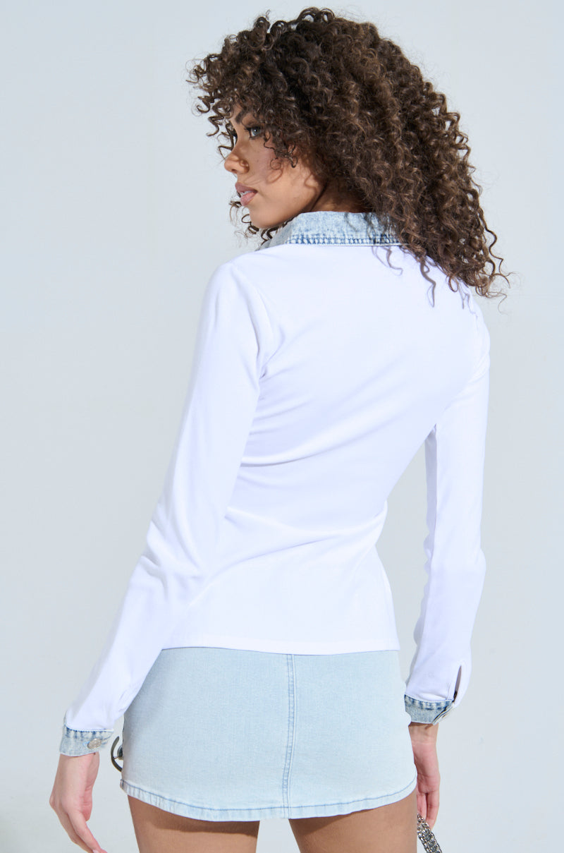 A curly-haired individual wears a RIB KNIT DENIM TRIM BUTTON DOWN COLLARED SHIRT IN WHITE and a light denim mini skirt, glancing over their shoulder against a light background.