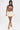 A woman in glasses wears the RAWR TANK, a sleeveless crop top with a tiger face print, paired with a layered cream mini skirt and tan knee-high boots with buckles, walking confidently against a plain white background.