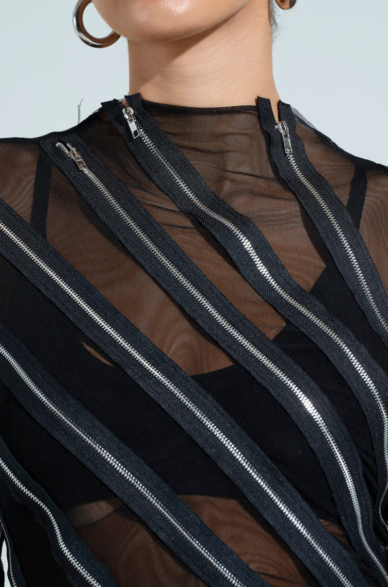 Close-up of someone wearing the CROSS ZIP MESH TOP in sheer black mesh with vertical zippers, paired with a mock neck undergarment. Large hoop earring enhances the outfit's intricate details.